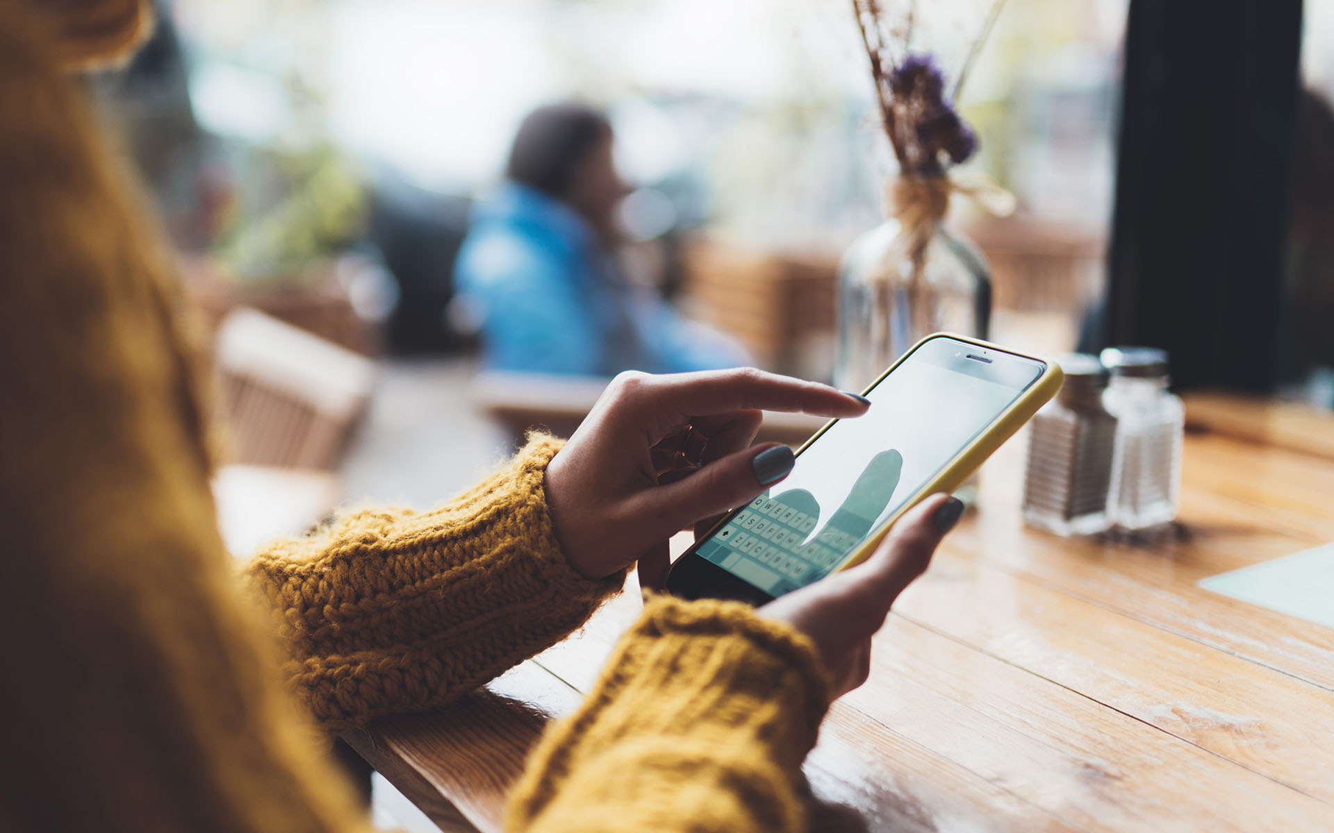 Atendimento via redes socias: Como organizar sua rotina. Pessoa de pele morena médio e blusa de manga comprida amarela com celular na mão respondendo alguem no whastapp