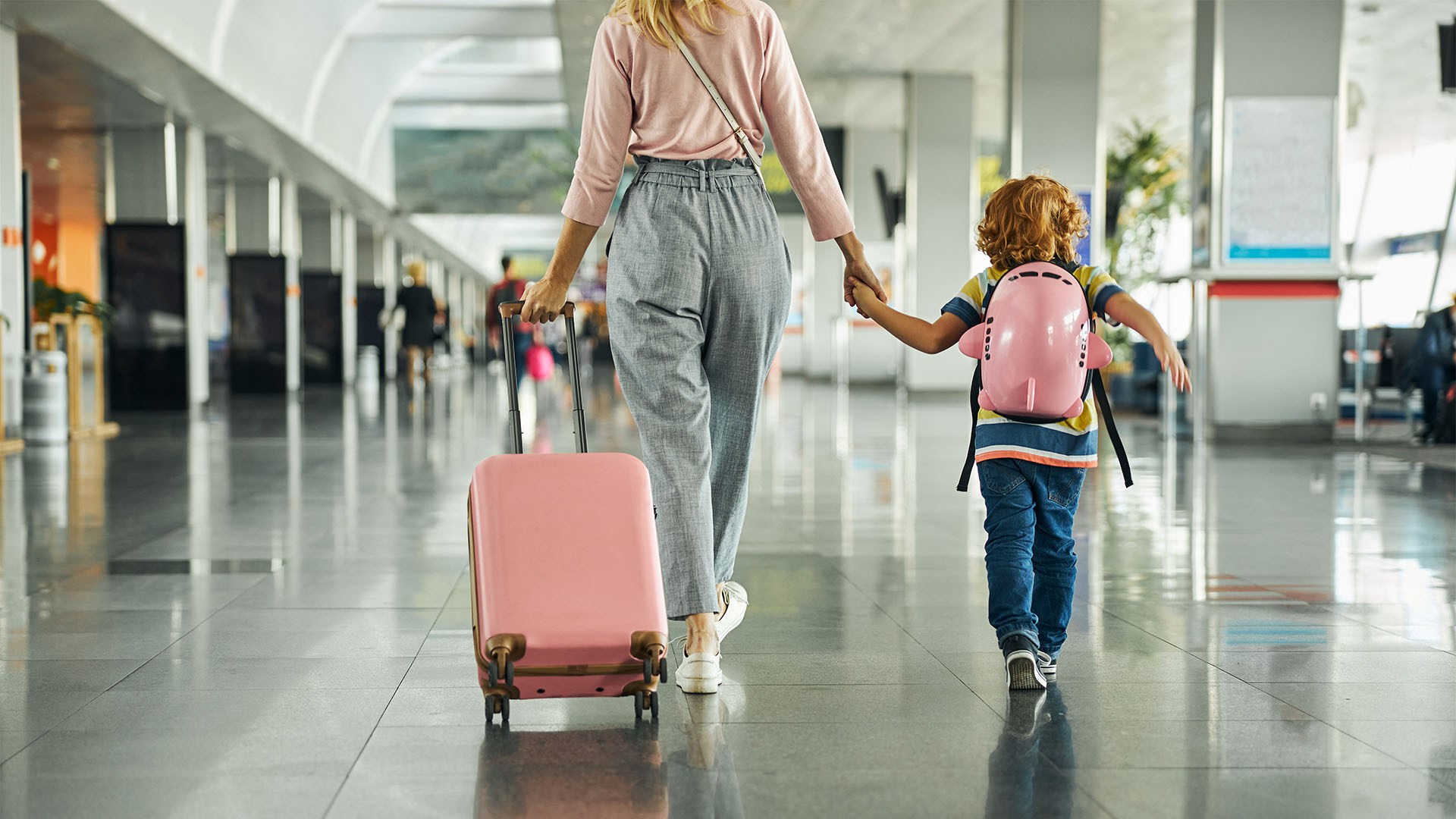 Tendências de recuperação do mercado de turismo mulher em aeroporto com mala em mãos segurando uma criança